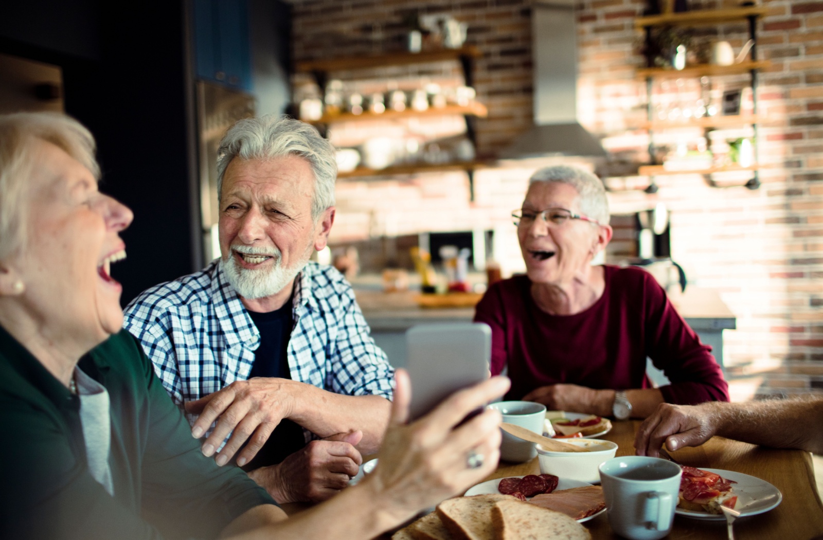 Three older people get together to share lunch and laughter.