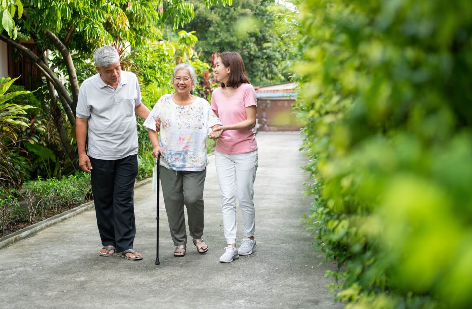 A senior gets assistance from their partner and adult child to get more practice walking outdoors to improve balance