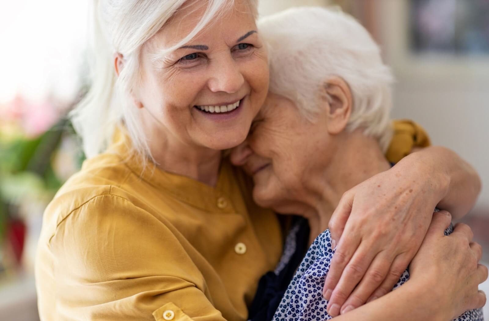 Two older adults smile and hug each other closely after a dementia test