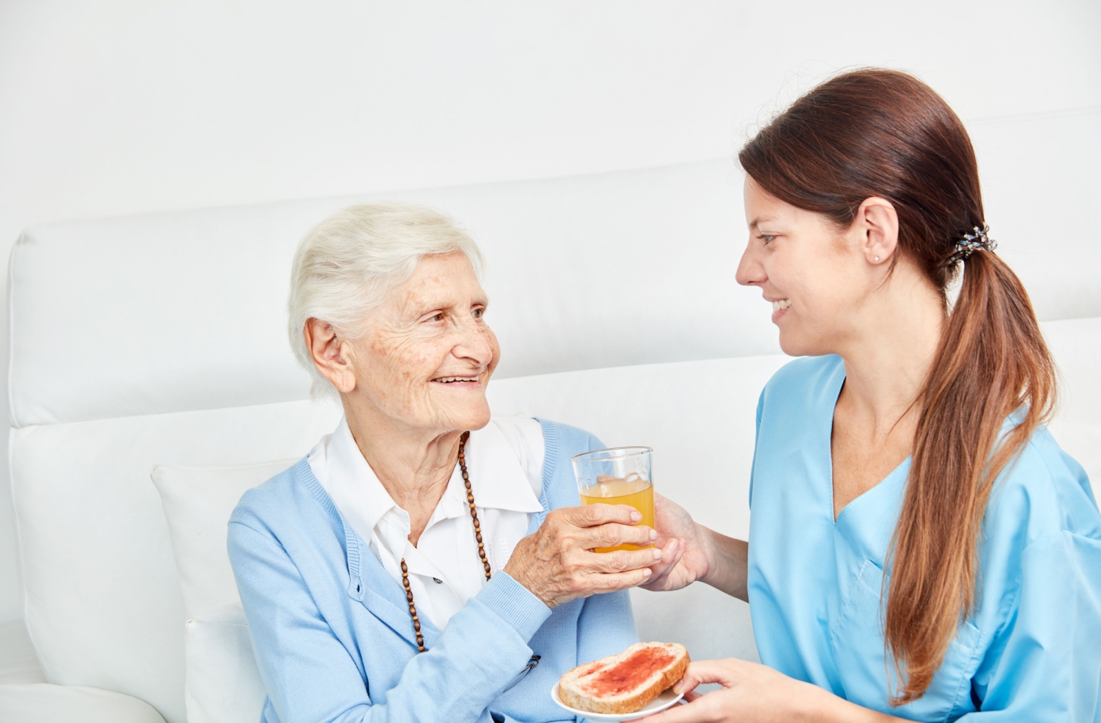 A personal care staff serving snacks to a senior woman.