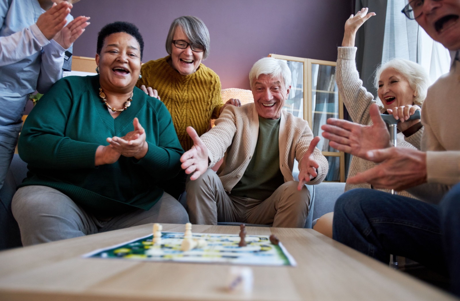 A group of seniors playing a board game smiling and cheering