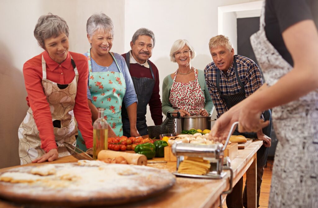 A group of seniors in a cooking class smiling and watching the teacher.