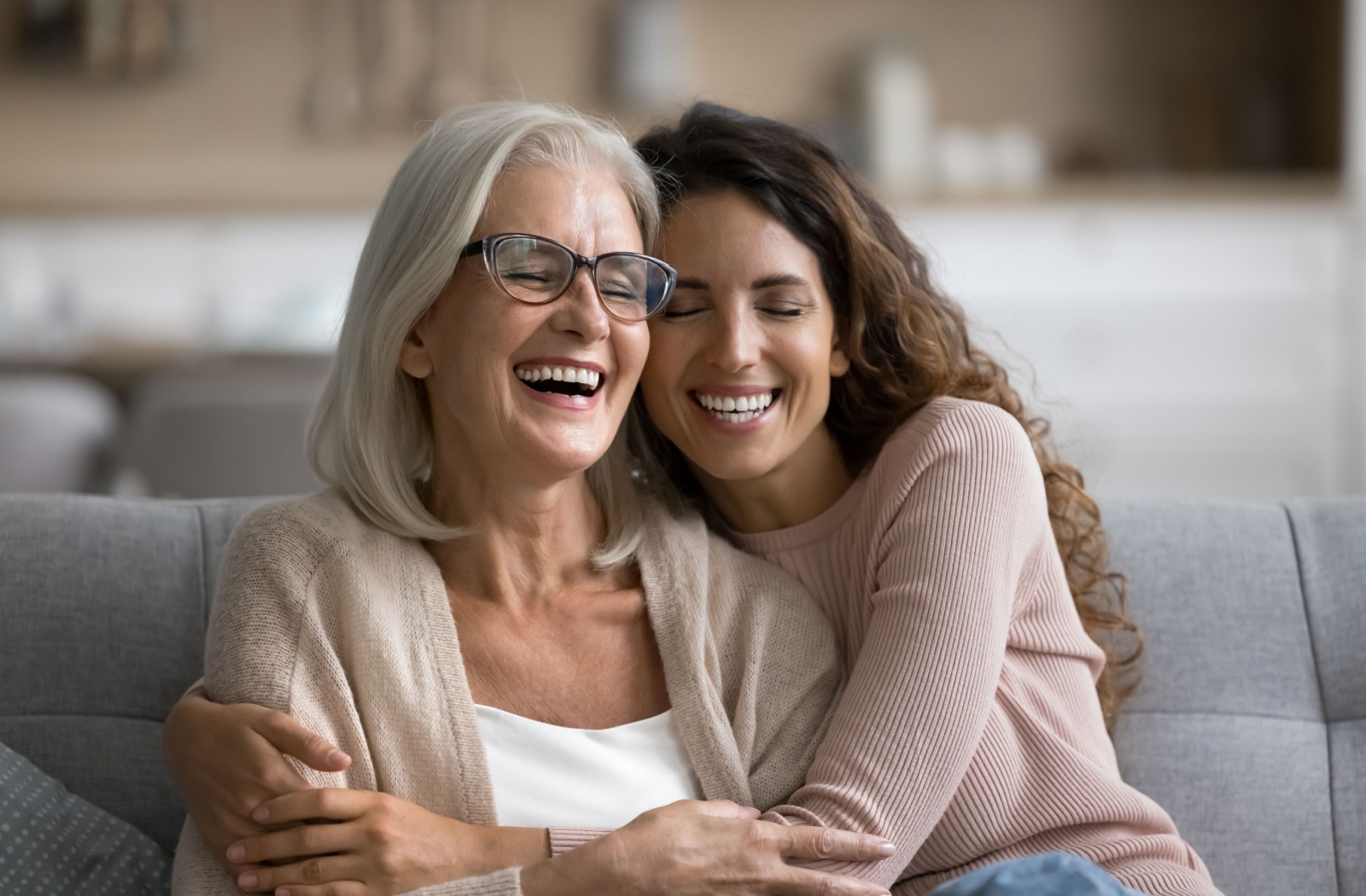 A happy senior and their adult child share a warm embrace as they discuss future senior care plans.