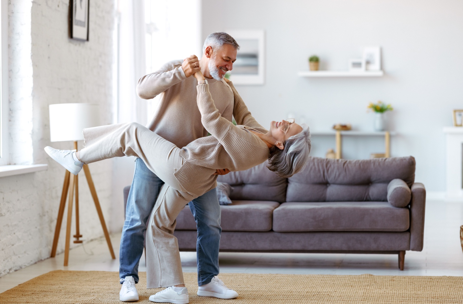 A happy senior couple keeps the romance alive by dancing together in their new personal care community home.