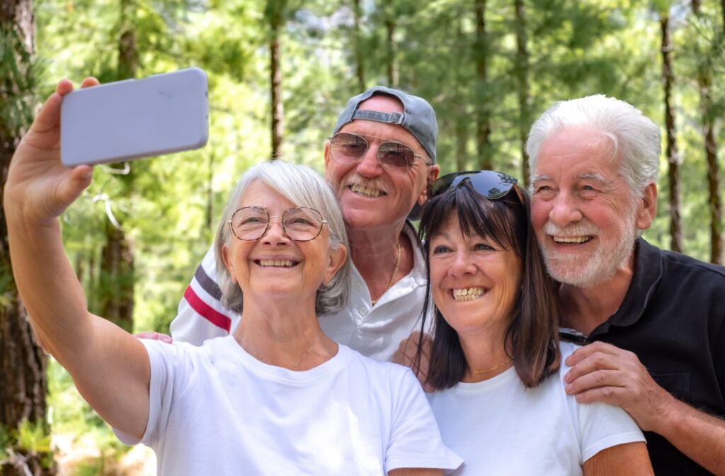 A group of smiling seniors take a selfie together as they enjoy an afternoon outside together.