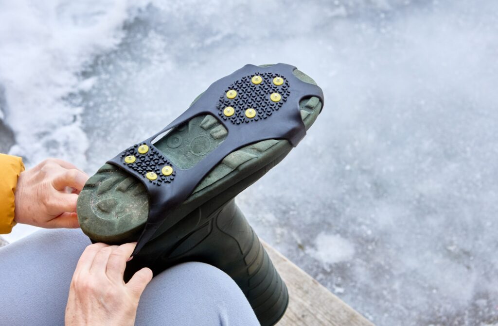 A close-up image of an older adult putting grips onto their winter boots for added safety.