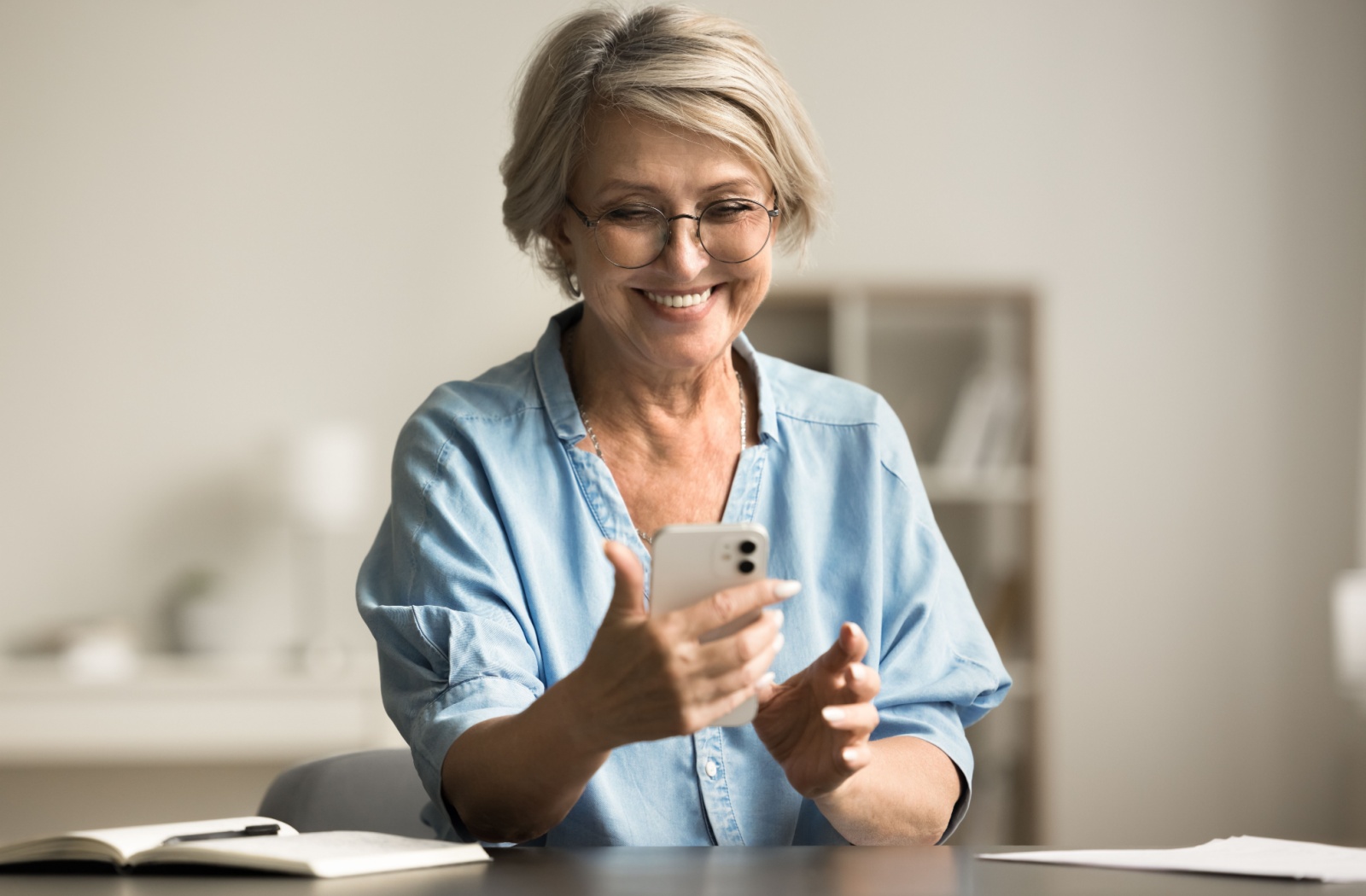 A happy senior uses their cell phone to stay in touch with loved ones.