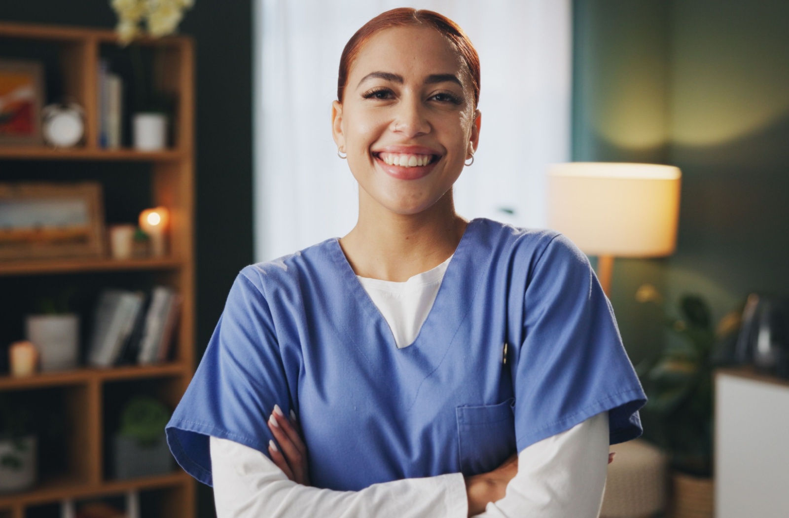 A smiling caregiver standing in the middle of a common room of a personal care community.