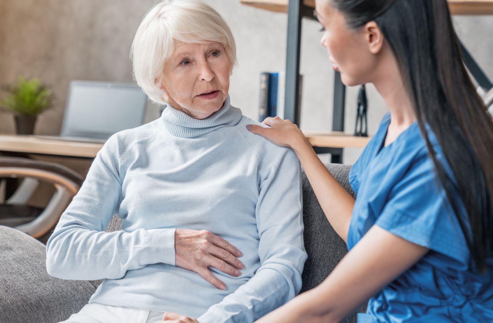 A caregiver comforts an older adult with dementia during a regular check-in in memory care